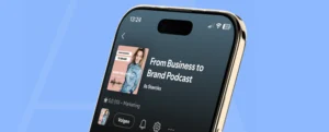Een smartphone toont de podcastpagina van "From Business to Brand Podcast" door Ils Sterckx op een blauwe achtergrond.