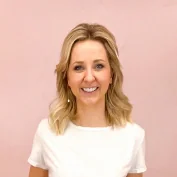 Portret van lachende vrouw met blond haar voor een roze achtergrond.