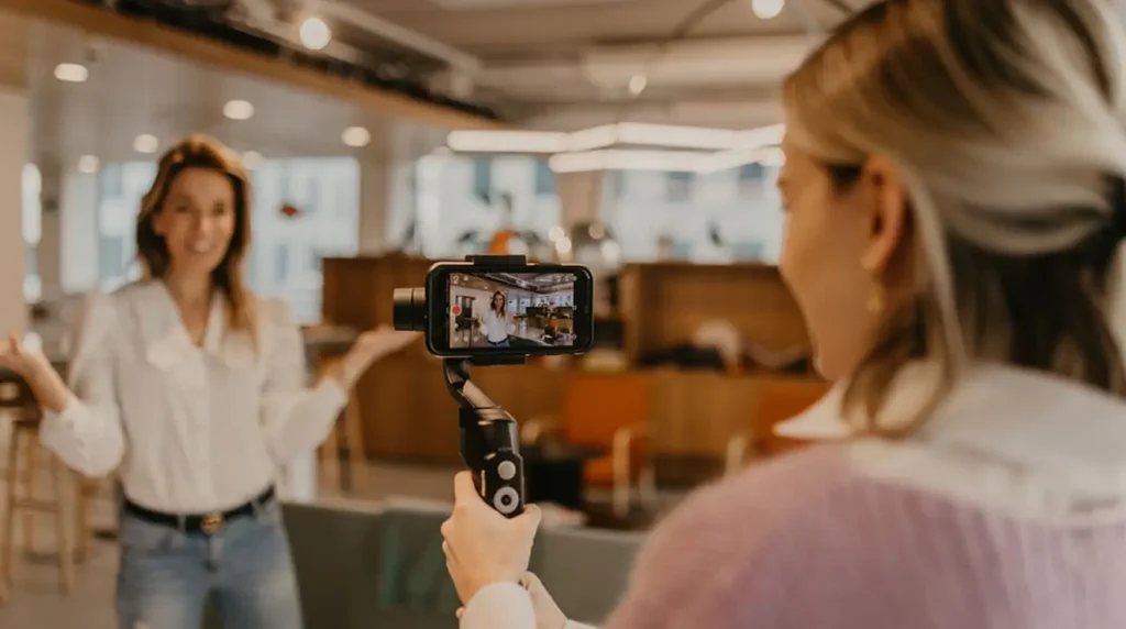 Een vrouw maakt een video-opname van een andere vrouw die praat in een moderne kantooromgeving.