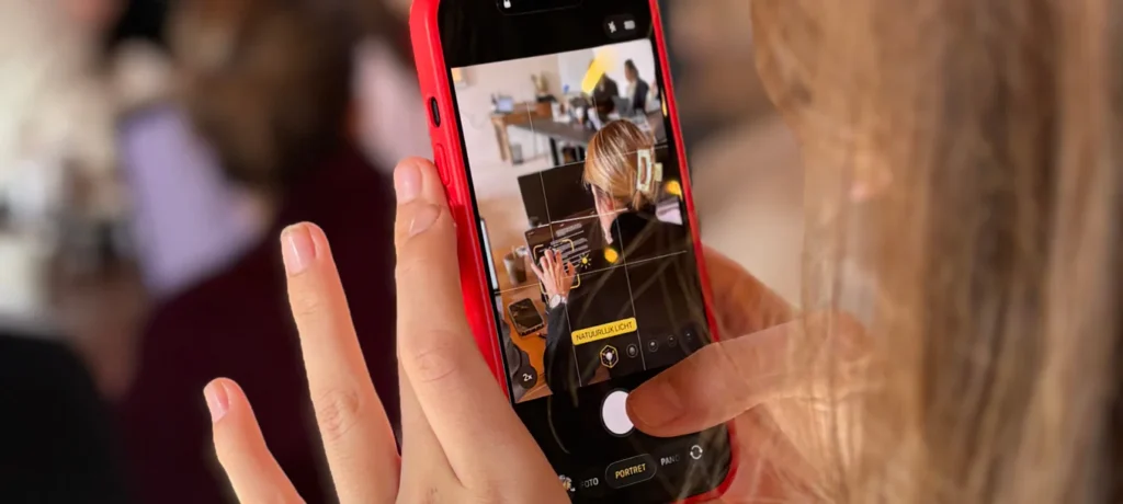 Een vrouw filmt een scène binnenshuis met een rode telefoon.
