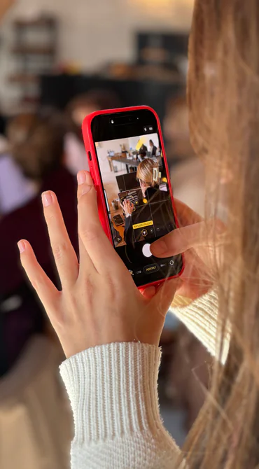 Een vrouw filmt met een rode telefoon in een binnensituatie.