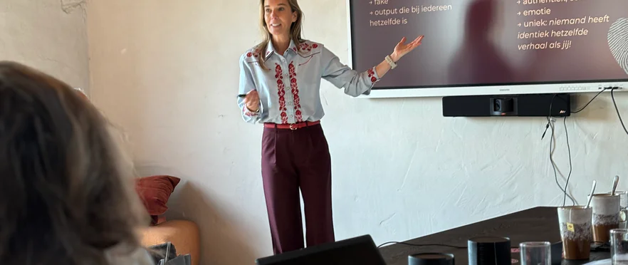 Een vrouw geeft een presentatie over marketing voor een scherm met tekst in een vergaderruimte.