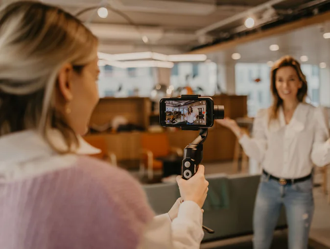 Een vrouw filmt een andere vrouw binnenshuis met een smartphone op een gimbal.